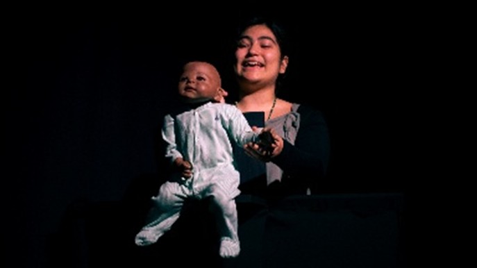 Une comedienne tient une marionnette de bébé
